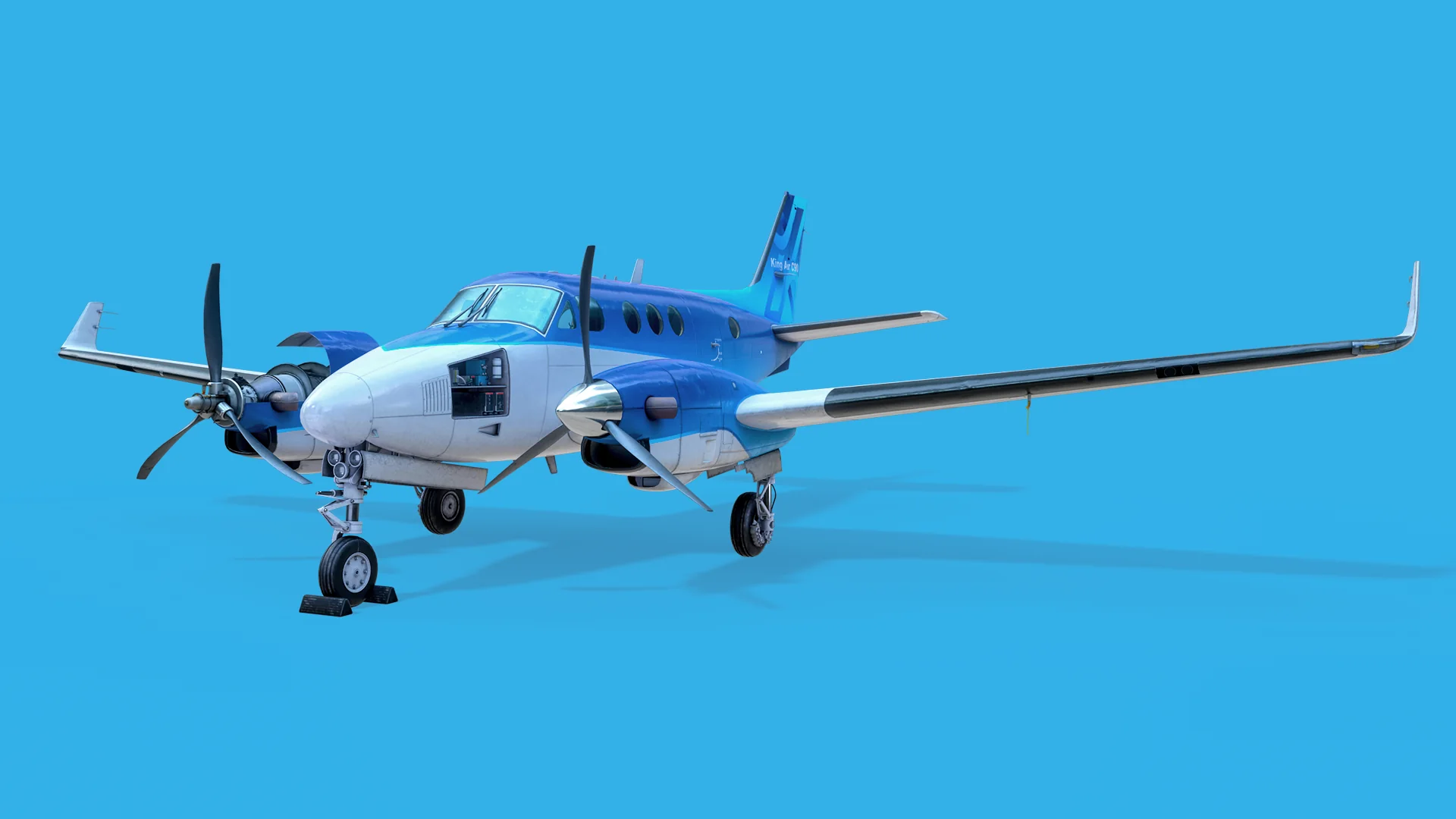 King Air C90 on the ground, front three-quarter view with chocks at the nose wheel.