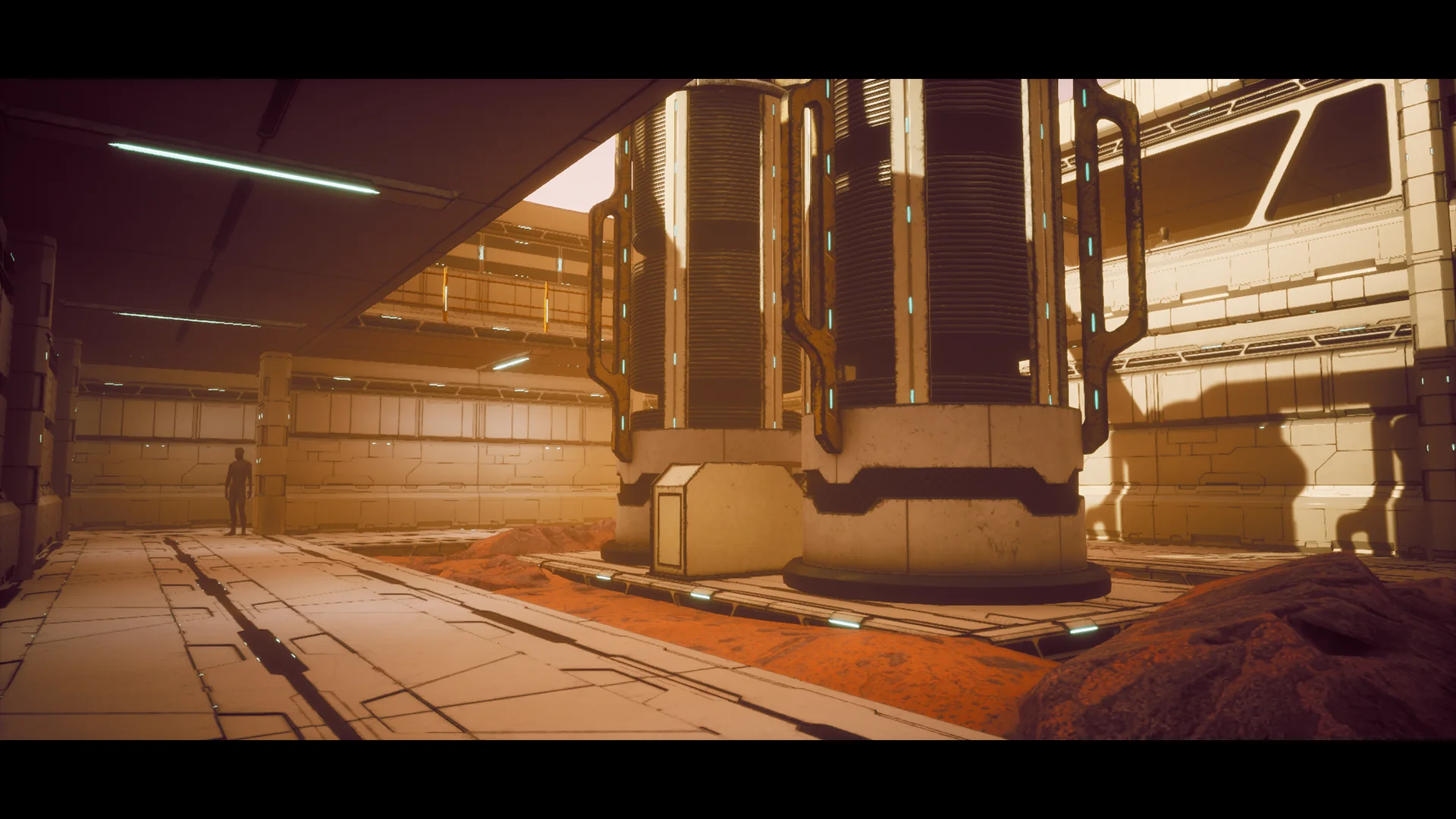 Interior hall with the reactor columns on the right, a figure for scale on the left and exposed red rock across the floor.